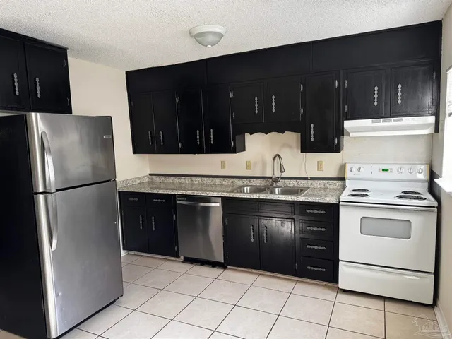a kitchen with granite countertop a refrigerator and a stove