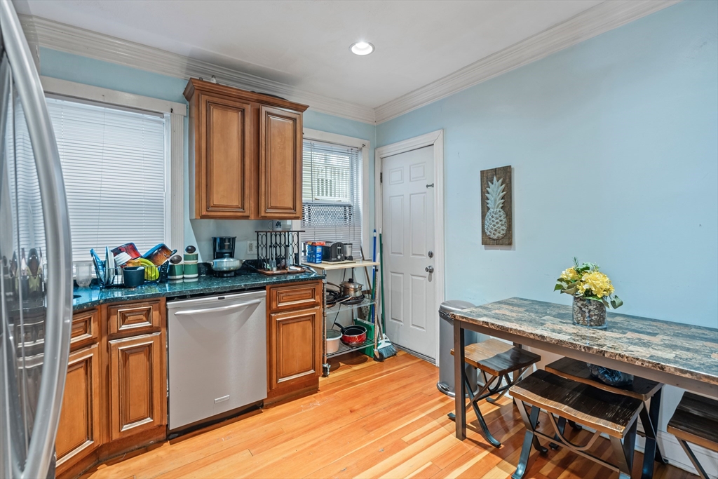 385 Centre Street, Unit 1 Boston, MA 02122 - Photo 3 of 14 a kitchen with stainless steel appliances kitchen island granite countertop wooden cabinets and dining table