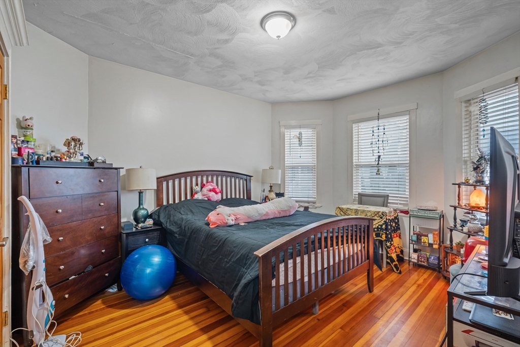 385 Centre Street, Unit 1 Boston, MA 02122 - Photo 6 of 14 a bedroom with a bed and wooden floor