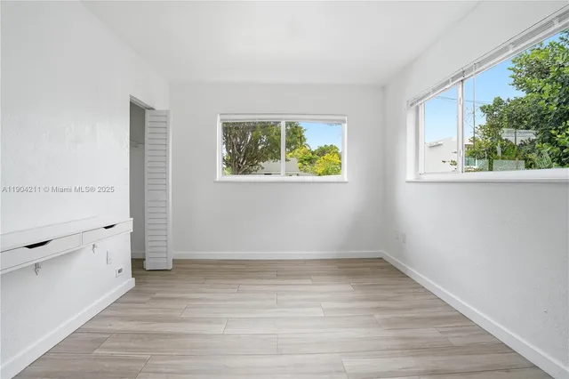 a view of an empty room with a window and wooden floor