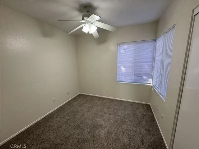 an empty room with a chandelier fan and wooden floor