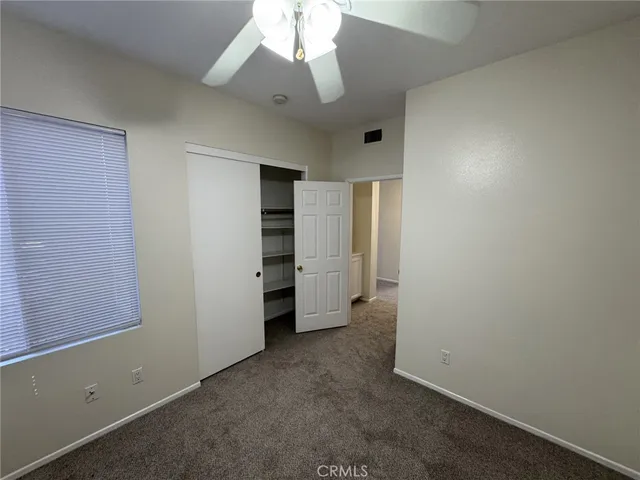 an empty room with closet and a ceiling fan