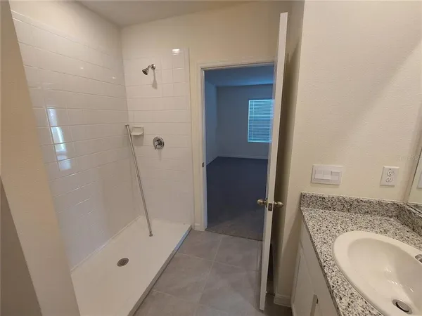 a bathroom with a granite countertop sink a mirror and shower