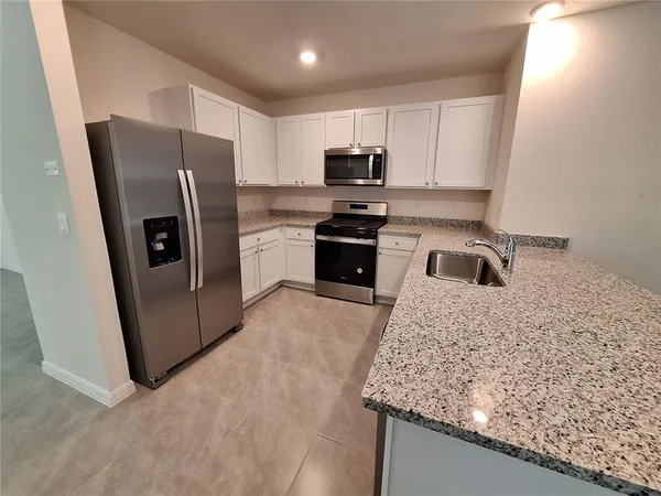 a kitchen with stainless steel appliances granite countertop a refrigerator sink and stove