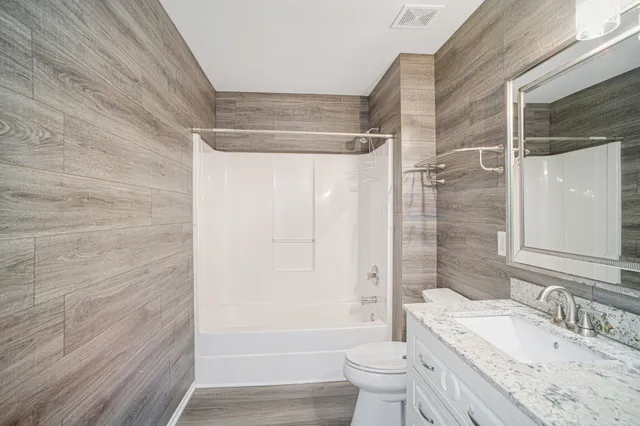 a bathroom with a granite countertop sink toilet and shower