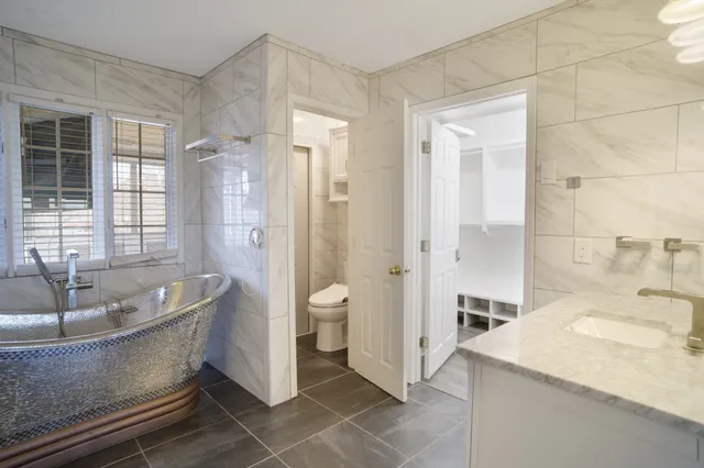 a spacious bathroom with a granite countertop sink a toilet a mirror and a tub
