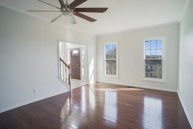 a view of an empty room with wooden floor and a window
