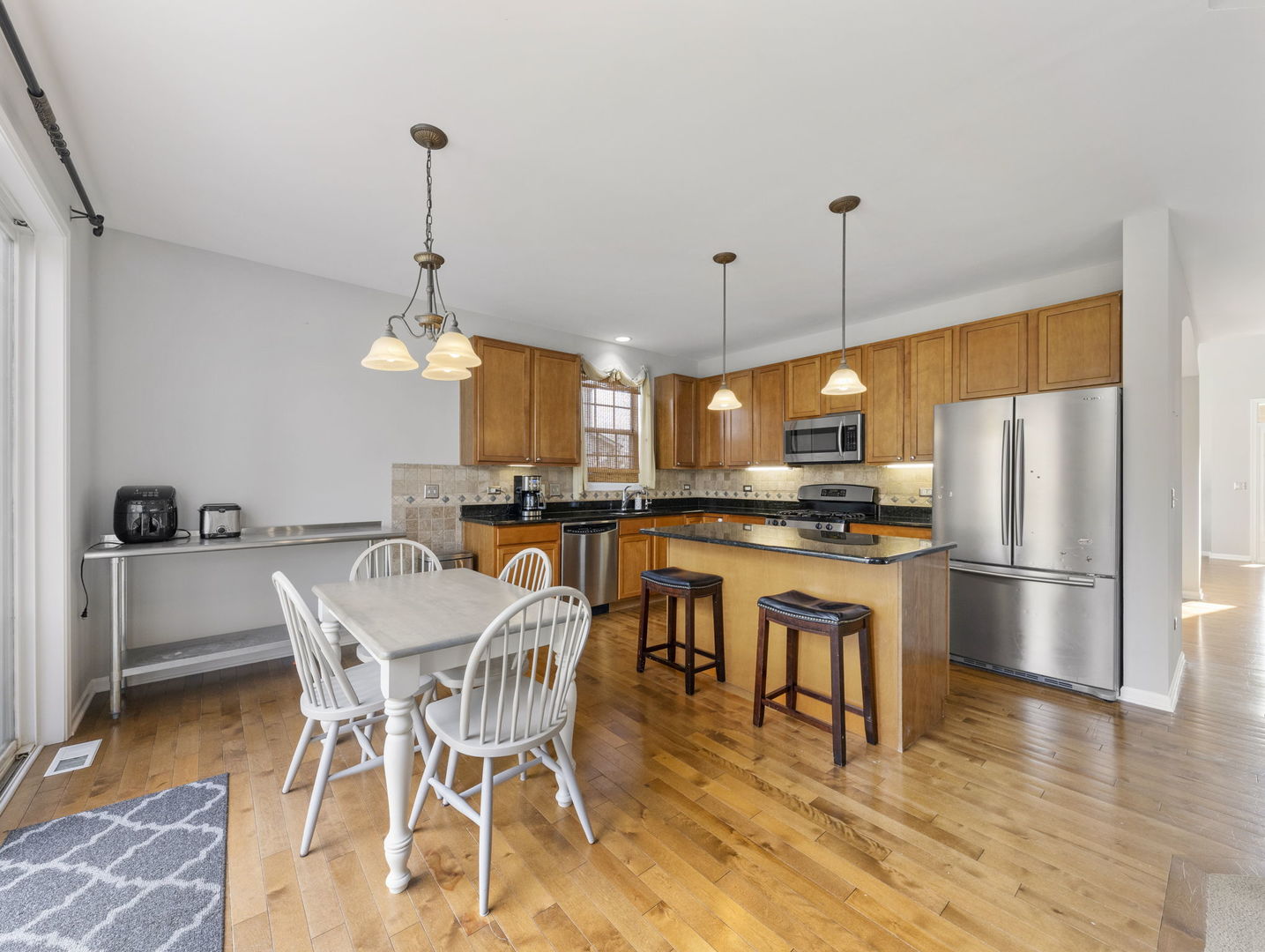 26528 Rustling Birch Way Plainfield, IL 60585 - Photo 7 of 39 a kitchen with stainless steel appliances granite countertop a refrigerator a microwave a stove and a dining table with wooden floor
