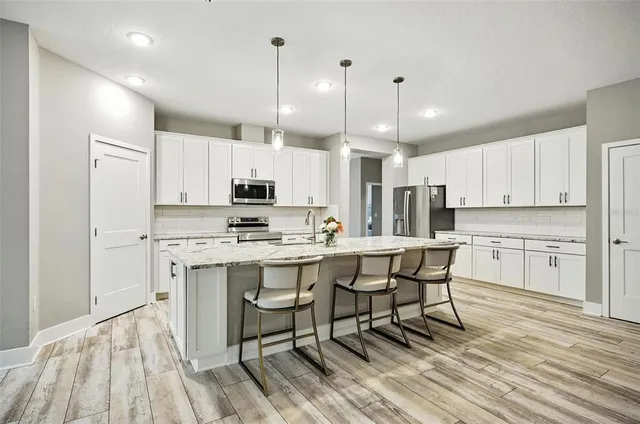 a kitchen with stainless steel appliances granite countertop a table and chairs in it
