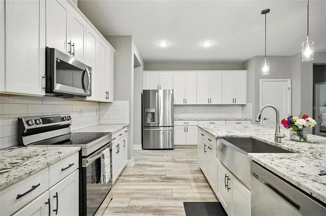 a kitchen with granite countertop white cabinets and stainless steel appliances