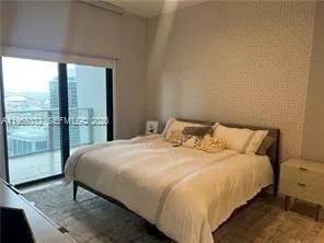 a bedroom with a bed and large windows