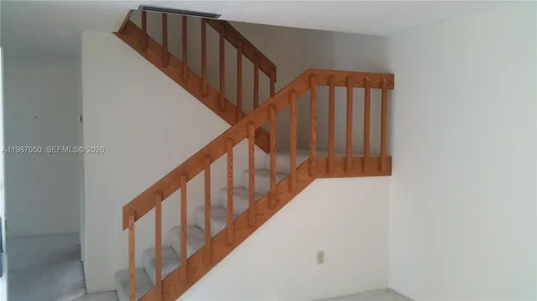 a view of staircase with wooden floor and white walls