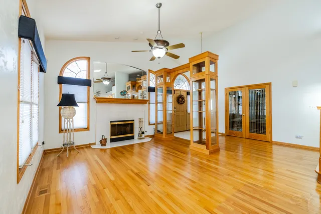 a view of a livingroom with wooden floor a fireplace a chandelier and wooden floor