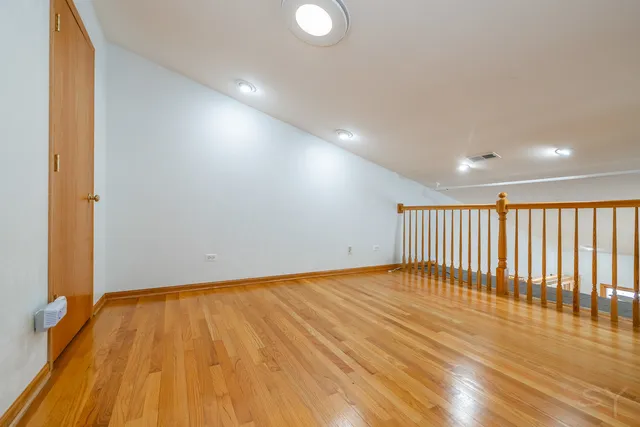 a view of empty room with wooden floor and fan