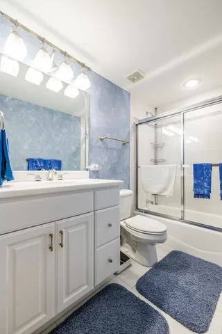 a bathroom with a toilet a sink a mirror and a shower