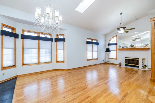 a view of an empty room with wooden floor fireplace and a window