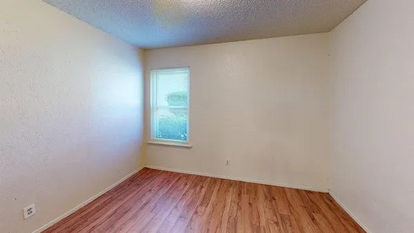 a view of empty room with wooden floor and entryway