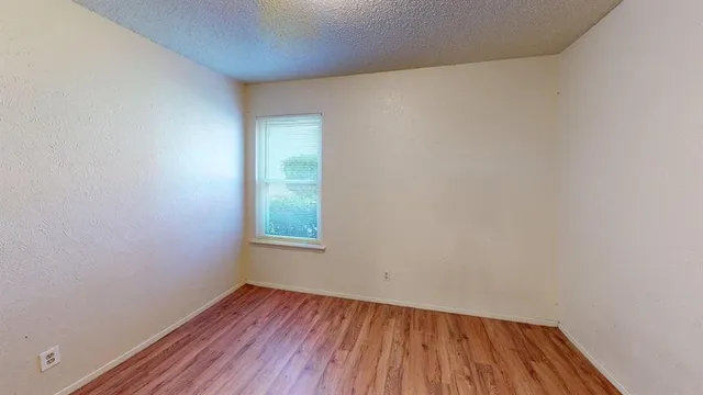 a view of empty room with wooden floor and entryway