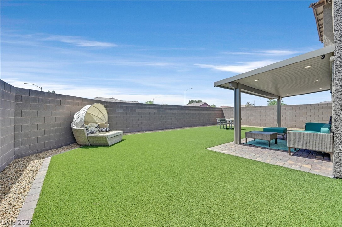 2933 Little Current Road North Las Vegas, NV 89086 - Photo 34 of 35 An inviting backyard oasis features a covered patio with paved flooring and vibrant green turf.