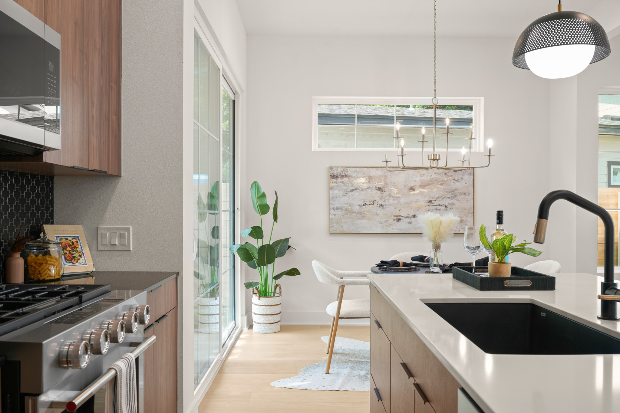 601 Vermont Road, Unit 2 Austin, TX 78702 - Photo 13 of 31 Culinary adventures await in this modern kitchen, boasting an island with a sleek sink and a dining area illuminated by elegant chandeliers.