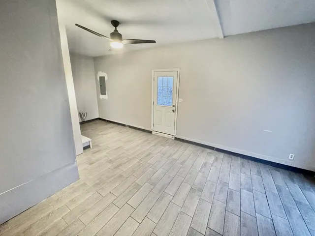 a view of an empty room with wooden floor and a window