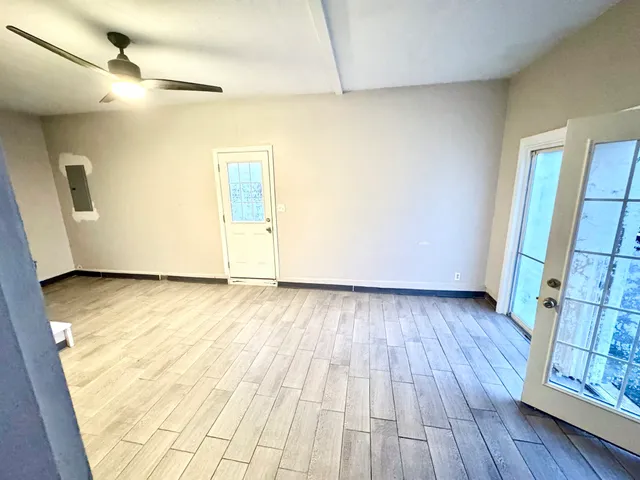 a view of an empty room with wooden floor and a window