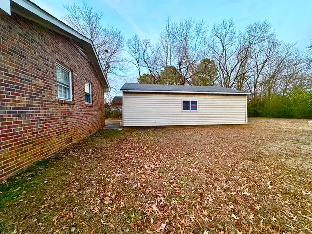 a backyard of a house with large trees and plants