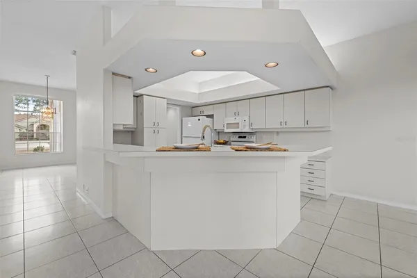 an empty room with wooden floor chandelier fan and windows