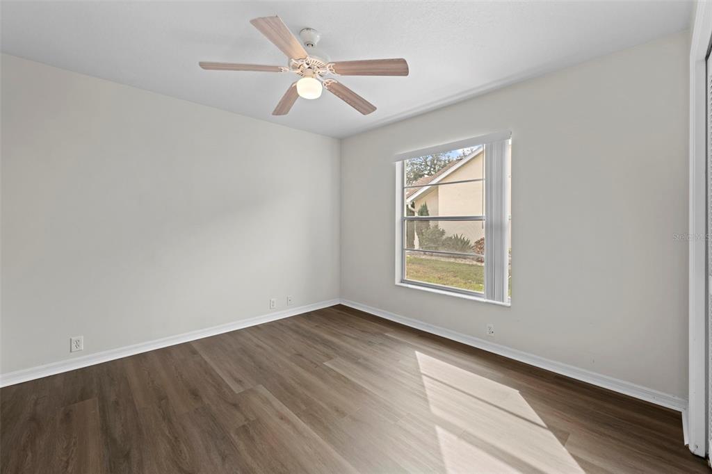 9369 Ashley Drive Weeki Wachee, FL 34613 - Photo 38 of 80 an empty room with wooden floor chandelier fan and windows