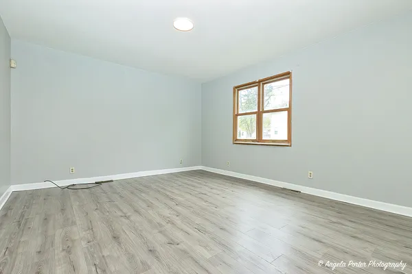 an empty room with wooden floor and windows