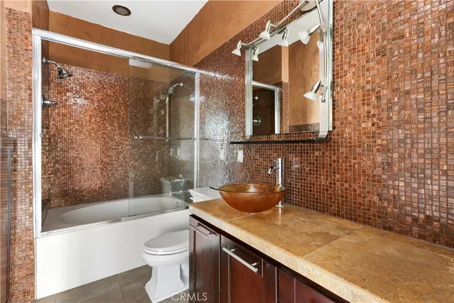 a bathroom with a granite countertop sink a toilet and shower