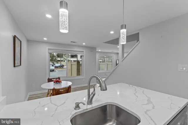 a kitchen with a stove a sink a refrigerator and a dining table with wooden floor