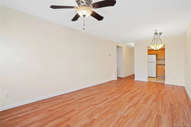 a view of an empty room with wooden floor and a ceiling fan