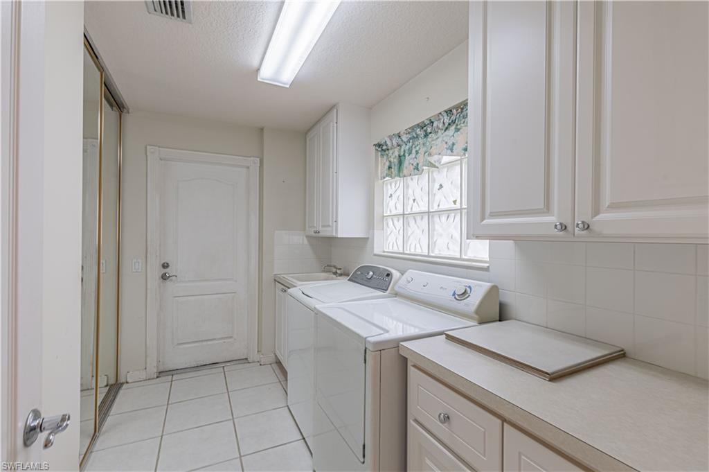 4187 St George Lane Naples, FL 34119 - Photo 21 of 33 a utility room with cabinets washer and dryer