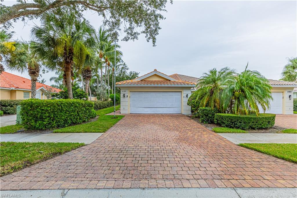 4187 St George Lane Naples, FL 34119 - Photo 22 of 33 a front view of a house with a garden and trees