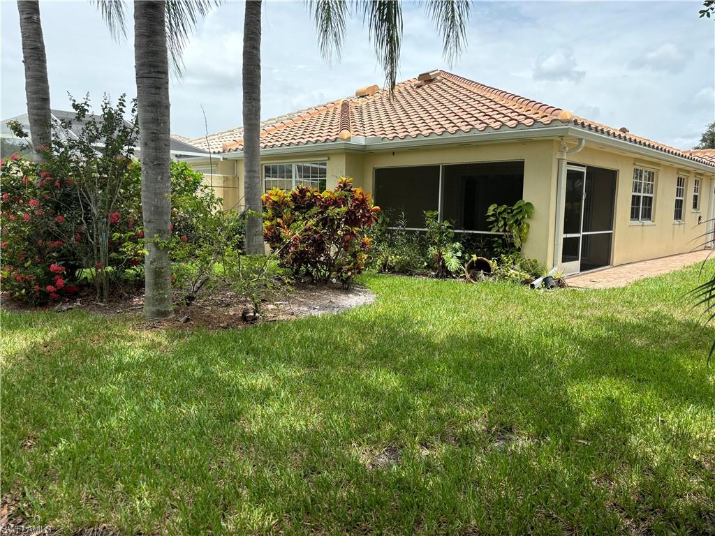 4187 St George Lane Naples, FL 34119 - Photo 24 of 33 a view of a house with a yard potted plants and a table