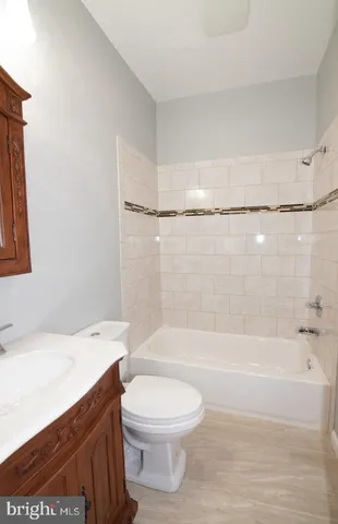 a bathroom with a bathtub shower sink vanity and toilet