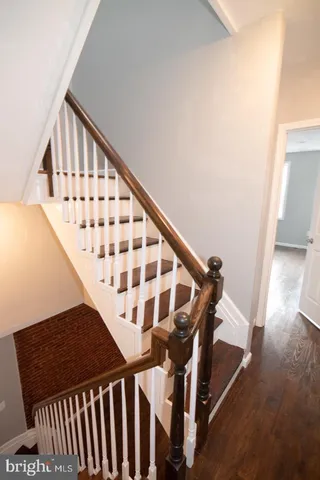 a view of staircase with wooden floor and white walls