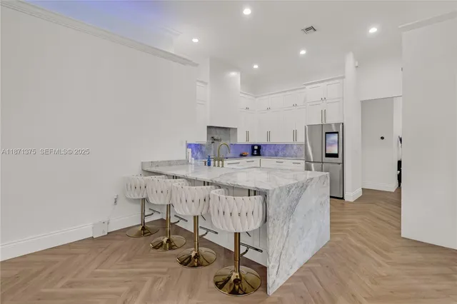 a kitchen with stainless steel appliances granite countertop a sink dishwasher and a refrigerator with wooden floor