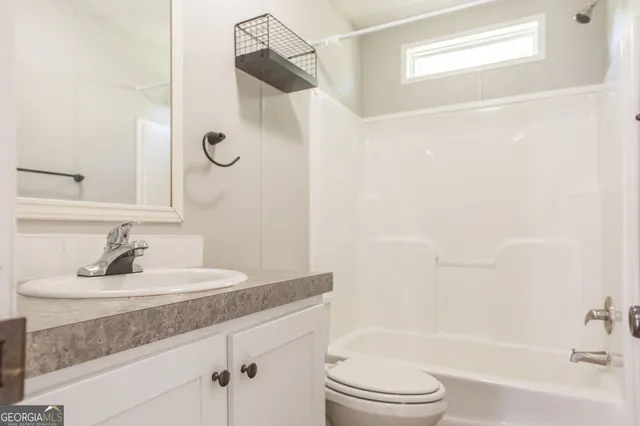 a bathroom with a granite countertop sink a toilet and shower