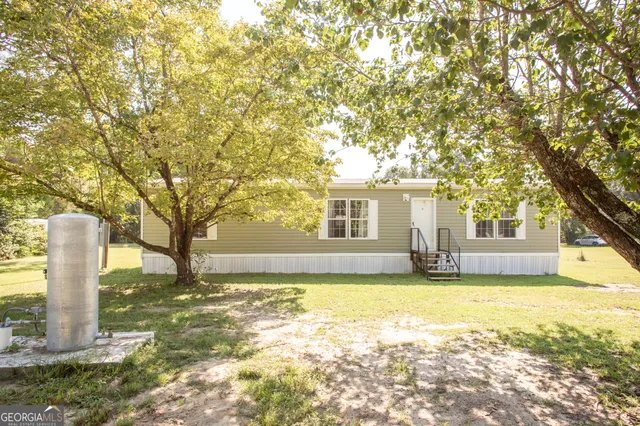 a view of a house with a yard and large trees