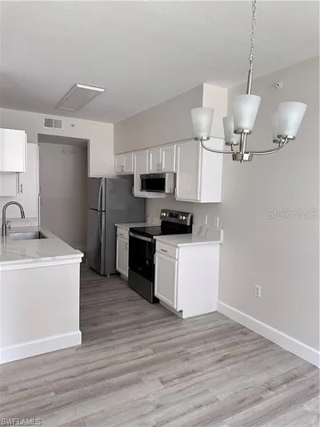 a kitchen with stainless steel appliances a sink cabinets and a wooden floor