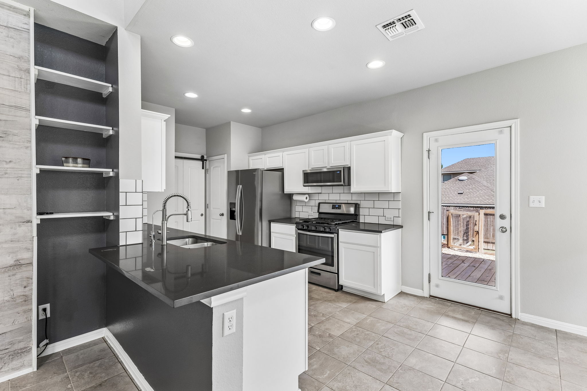 689 Nautical Loop Kyle, TX 78640 - Photo 10 of 34 A well-appointed kitchen features white cabinetry, dark countertops, and stainless steel appliances.