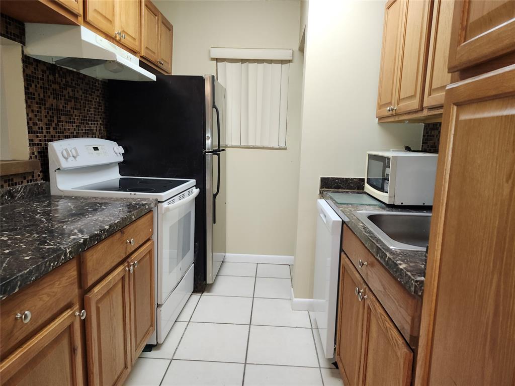 545 Trace Circle, Unit 105 Deerfield Beach, FL 33441 - Photo 12 of 44 a kitchen with stainless steel appliances granite countertop a refrigerator and a stove
