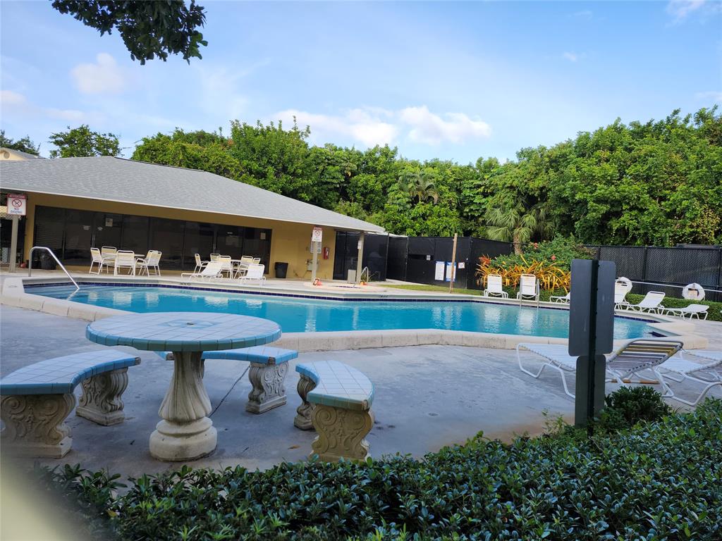 545 Trace Circle, Unit 105 Deerfield Beach, FL 33441 - Photo 3 of 44 a view of a swimming pool with a bench in patio