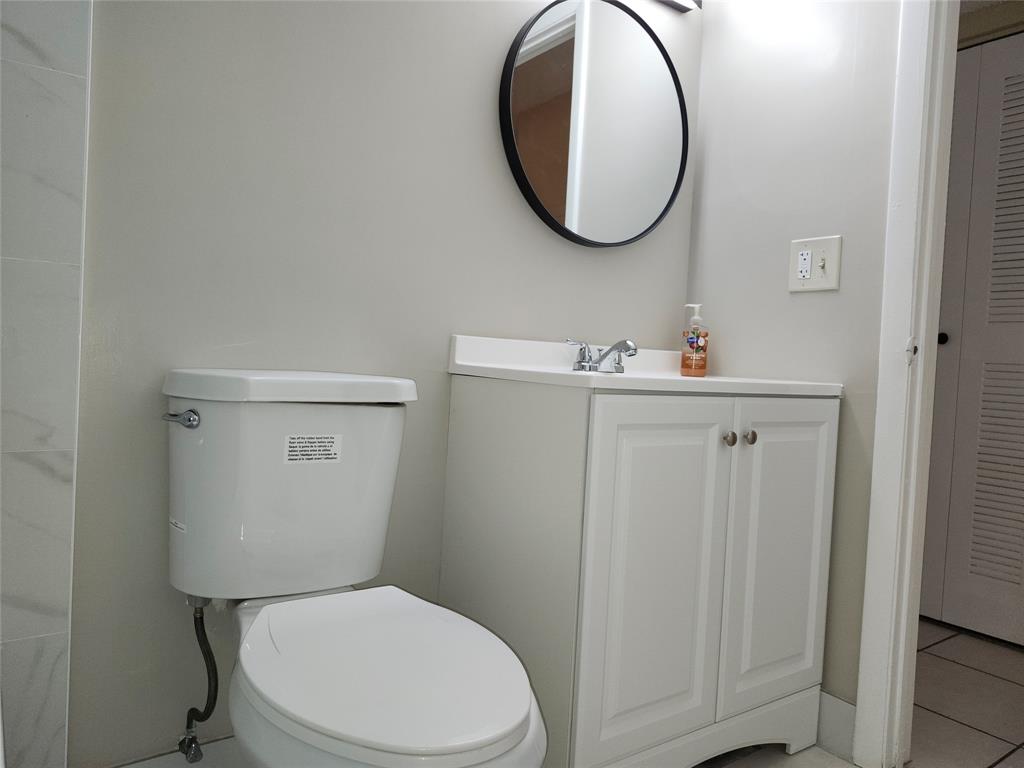 545 Trace Circle, Unit 105 Deerfield Beach, FL 33441 - Photo 38 of 44 a bathroom with a toilet a sink and a mirror