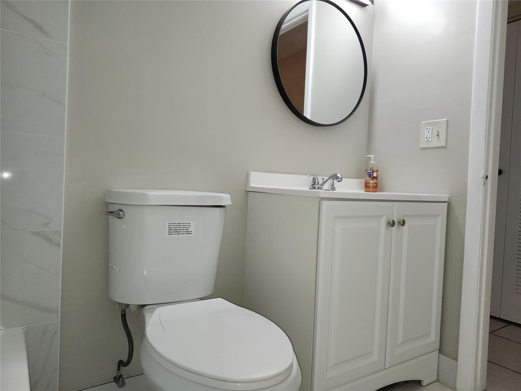 545 Trace Circle, Unit 105 Deerfield Beach, FL 33441 - Photo 41 of 44 a bathroom with a toilet a sink and mirror