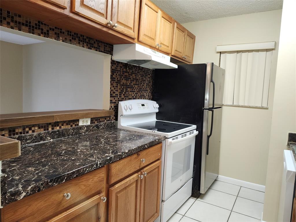 545 Trace Circle, Unit 105 Deerfield Beach, FL 33441 - Photo 10 of 44 a kitchen with stainless steel appliances granite countertop a refrigerator and a stove