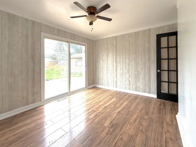 a view of an empty room with a window and wooden floor