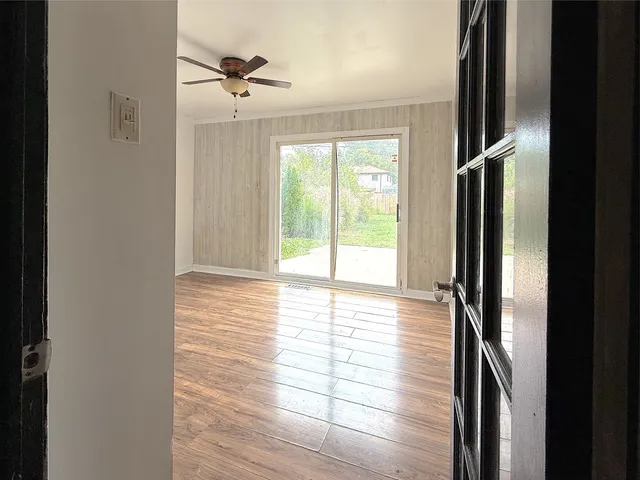 a view of an empty room with wooden floor and a window
